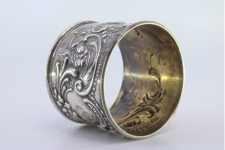 Argola de guardanapo em prata com flores e grinaldas relevadas envolvendo cartela para monograma.